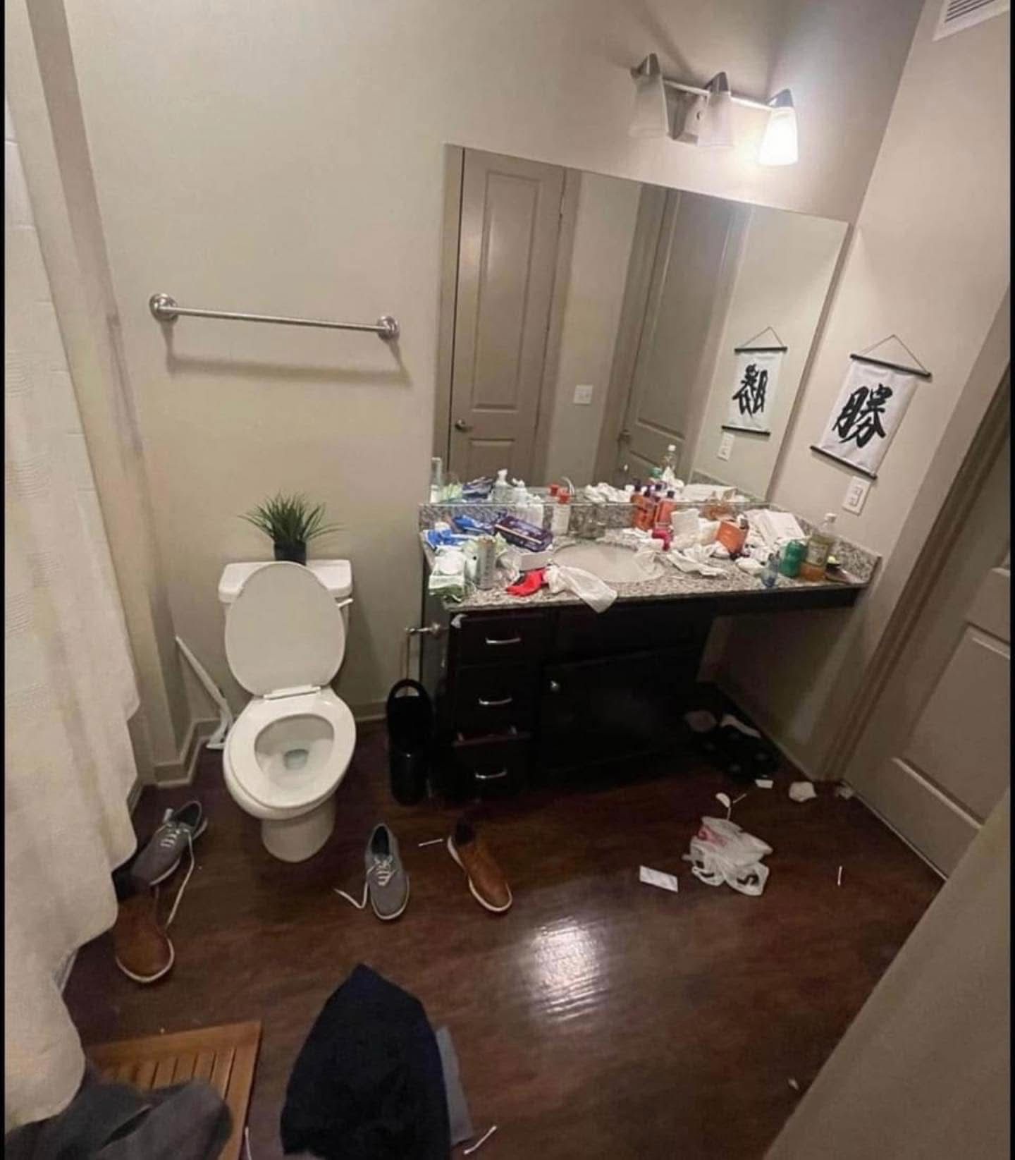 Bathroom before cleaning, cluttered with items on the counter and floor